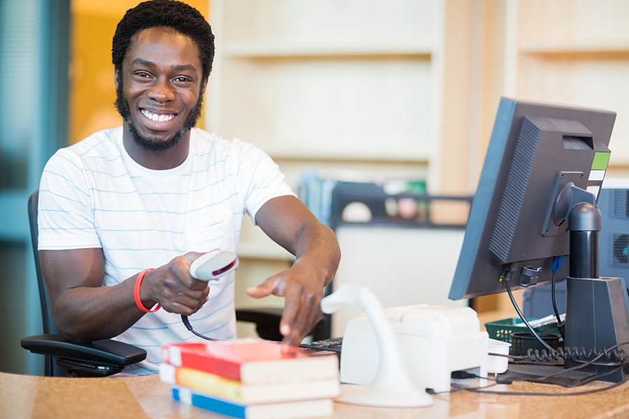 Male librarian checking out books at the circulation desk