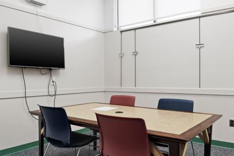 Corner shot of study room with small table, 4 chairs, and screen mounted on wall