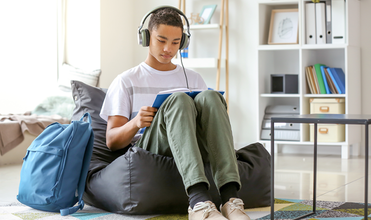 Teen boy sitting on beanbag with book in his lap